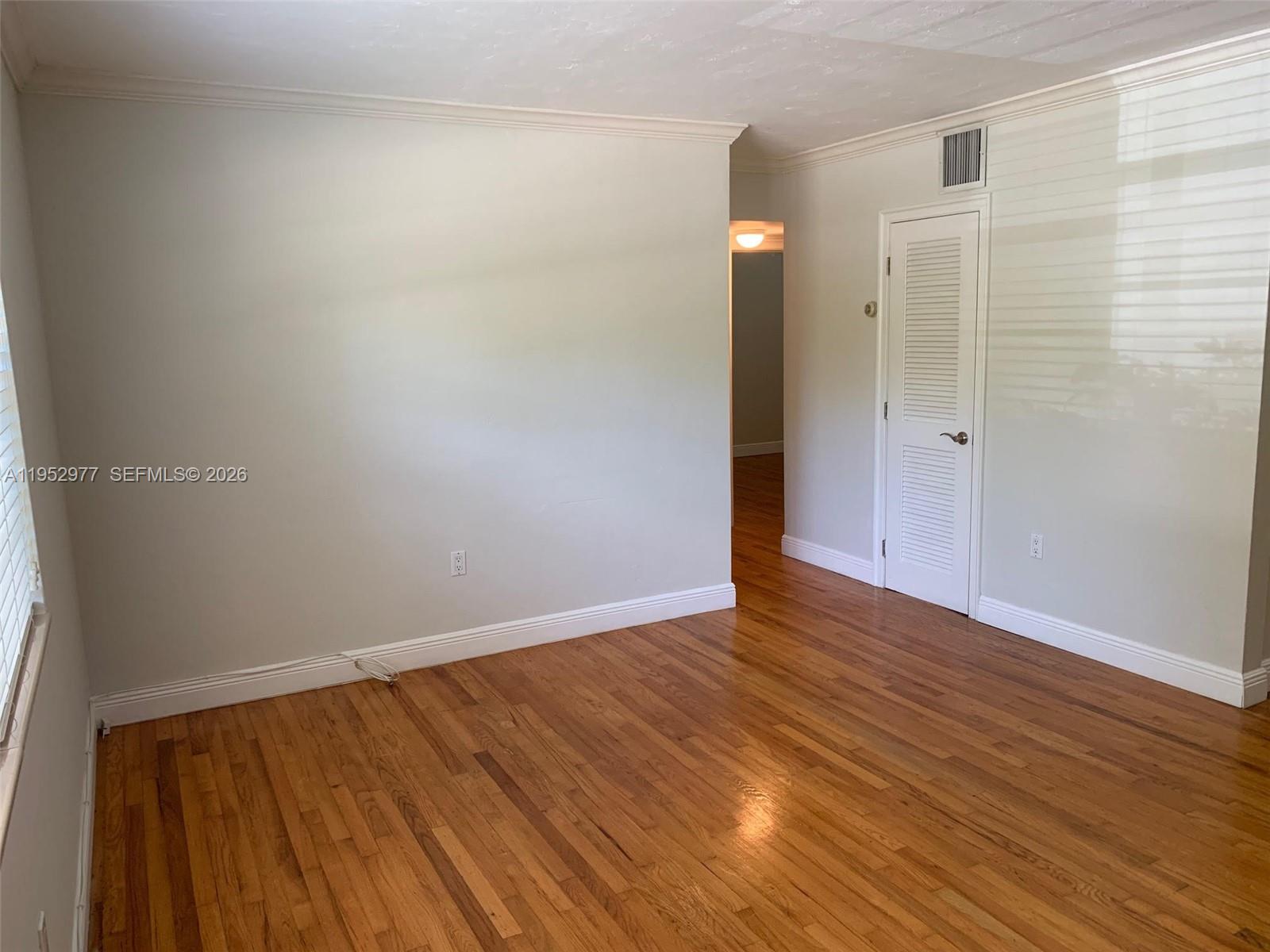 7840 Southwest 55th Avenue, Unit 22A Miami, FL 33143 - Photo 2 of 16 a view of an empty room with wooden floor and a window