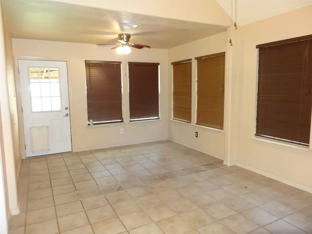 an empty room with windows and chandelier fan