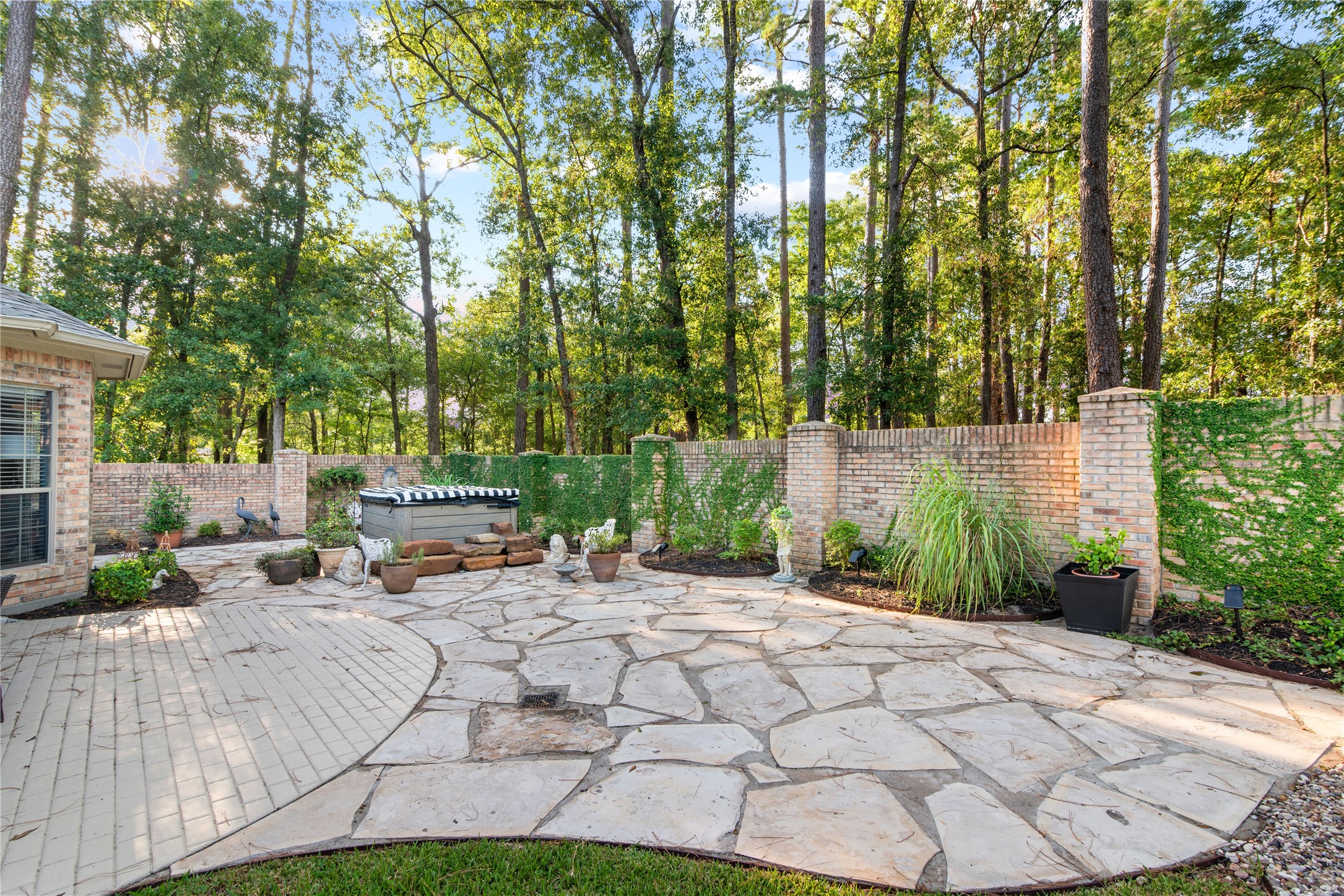 901 Longmire Road, Unit 51 Conroe, TX 77304 - Photo 6 of 48 Serene backyard oasis with a spacious flagstone patio, surrounded by lush greenery and a charming brick wall for privacy. Perfect for relaxation and entertaining.