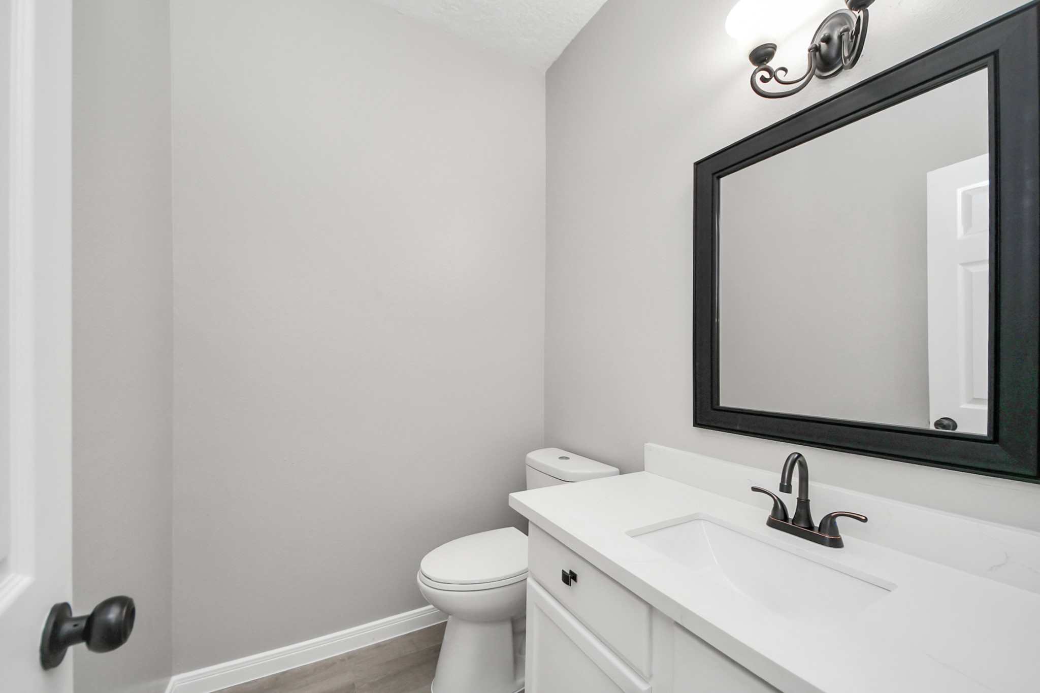 1105 East Kyle Road Clute, TX 77531 - Photo 15 of 44 The half-bathroom with a sleek white vanity, black fixtures, a large mirror, and a light fixture above.