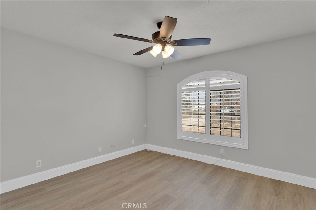 11410 Cibola Road Apple Valley, CA 92308 - Photo 30 of 45 an empty room with wooden floor chandelier fan and windows