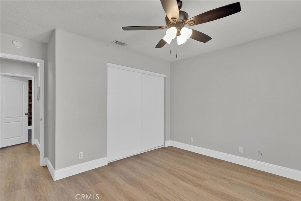 11410 Cibola Road Apple Valley, CA 92308 - Photo 31 of 45 an empty room with wooden floor fan and windows