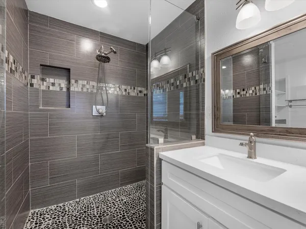 a bathroom with a shower sink and mirror