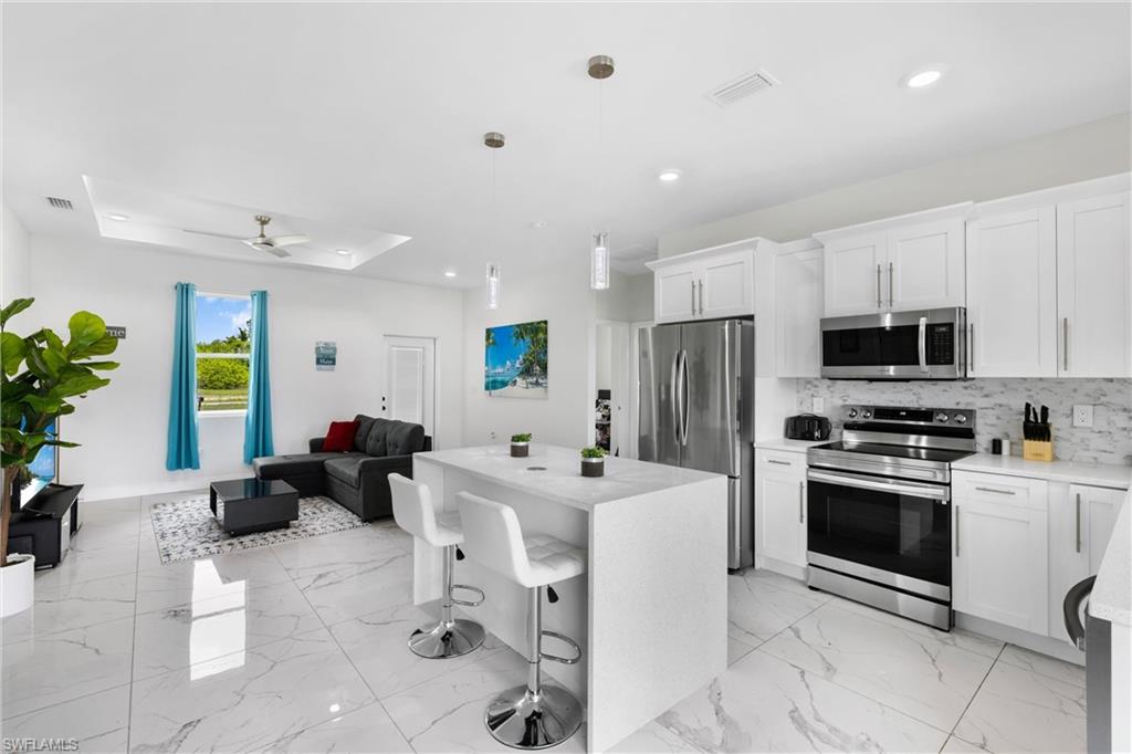 110 Nelson Road South Cape Coral, FL 33991 - Photo 11 of 27 a kitchen with stainless steel appliances kitchen island granite countertop a sink and cabinets