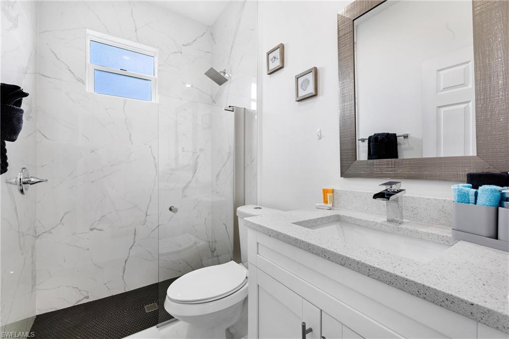 110 Nelson Road South Cape Coral, FL 33991 - Photo 22 of 27 a bathroom with a granite countertop sink a toilet and a mirror