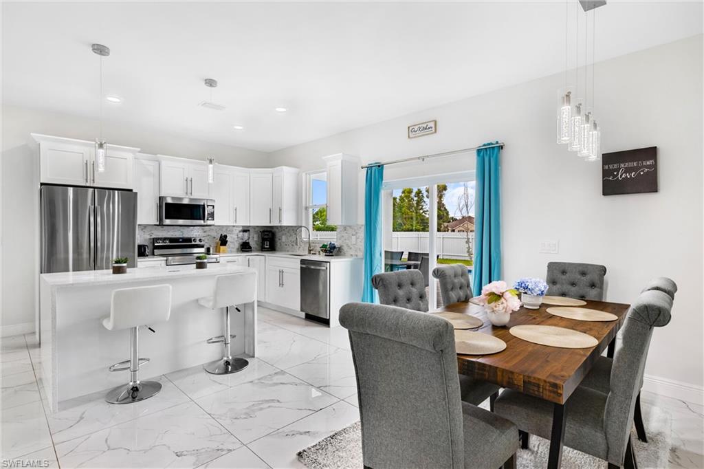 110 Nelson Road South Cape Coral, FL 33991 - Photo 6 of 27 a kitchen with stainless steel appliances kitchen island granite countertop a refrigerator a stove a sink dishwasher with a dining table and chairs