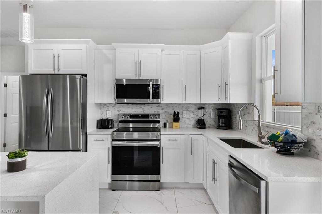 110 Nelson Road South Cape Coral, FL 33991 - Photo 8 of 27 a kitchen with white cabinets and stainless steel appliances