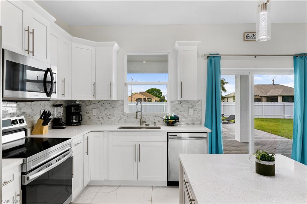 110 Nelson Road South Cape Coral, FL 33991 - Photo 9 of 27 a kitchen with white cabinets and appliances