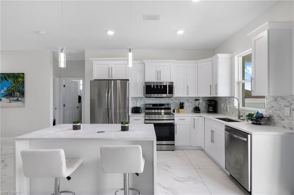 110 Nelson Road South Cape Coral, FL 33991 - Photo 10 of 27 a kitchen with stainless steel appliances a sink stove and refrigerator