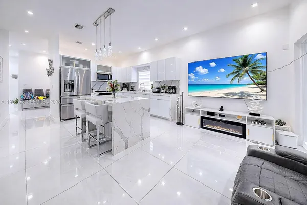 a large white kitchen with stainless steel appliances lots of counter space and breakfast area
