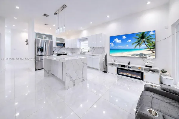 a large white kitchen with stainless steel appliances granite countertop a stove and a sink
