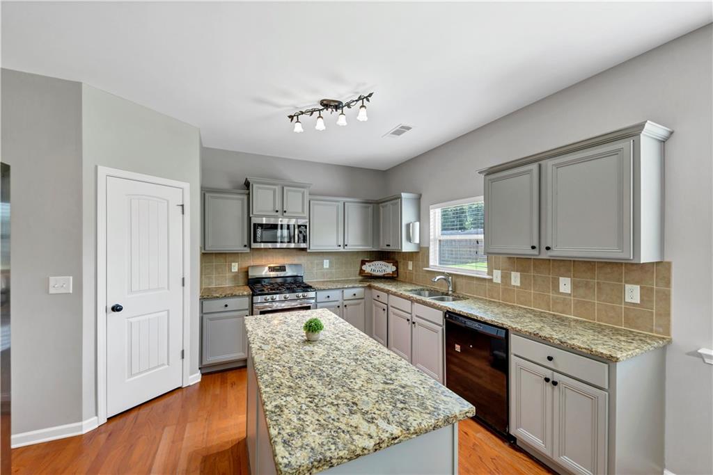 210 Creek View Lane Acworth, GA 30102 - Photo 12 of 48 a kitchen with stainless steel appliances granite countertop a stove top oven a sink dishwasher and a refrigerator with wooden floor