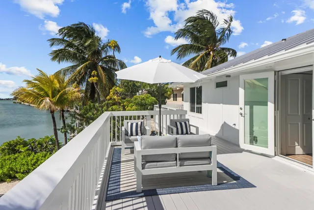 a view of a house with pool table and chairs next to a yard
