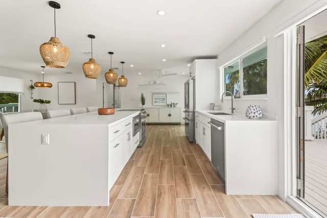 a large white kitchen with a large window a sink and stainless steel appliances