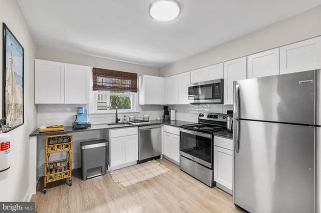 a kitchen with a refrigerator a stove top oven a sink dishwasher and white cabinets with wooden floor