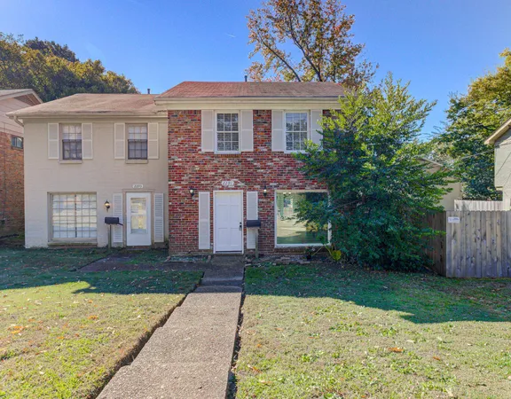 a front view of a house with a yard and trees