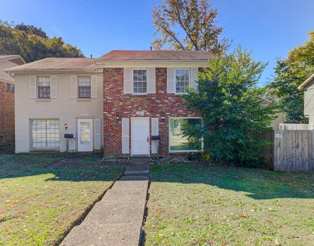a front view of a house with a yard and trees
