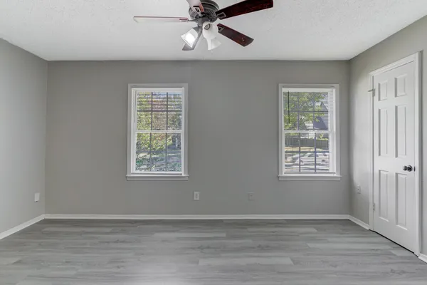 a view of an empty room with a window and wooden floor