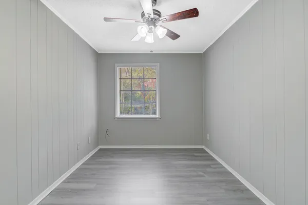 an empty room with a chandelier fan and windows