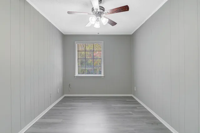an empty room with a chandelier fan and windows