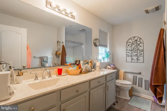 a bedroom with a bed a couch and dresser with wooden floor