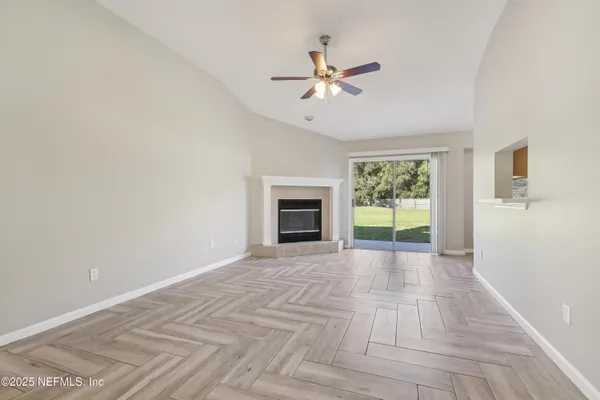 a view of an empty room with a window and fireplace