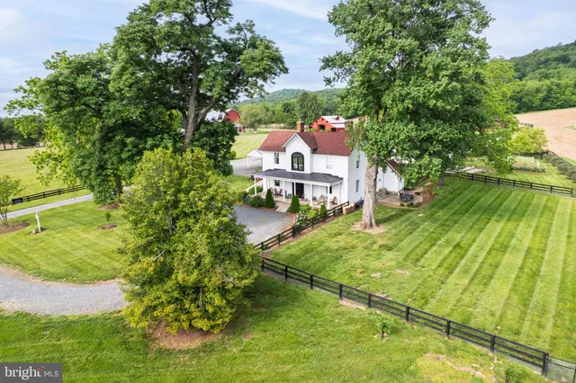 a view of a big house with a big yard and large trees