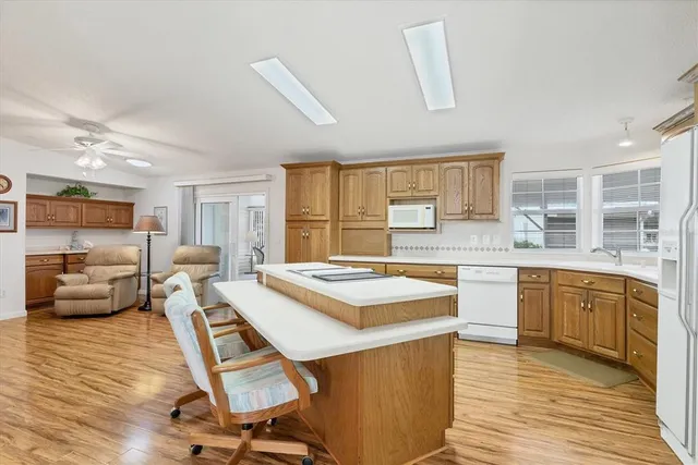 a kitchen with a stove a sink dishwasher a refrigerator and white cabinets with wooden floor