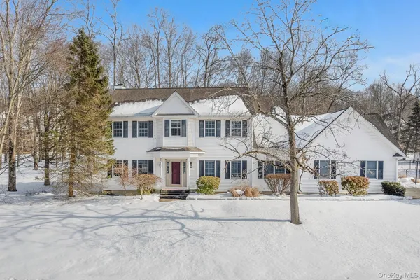 a front view of a building with a yard covered with snow and trees