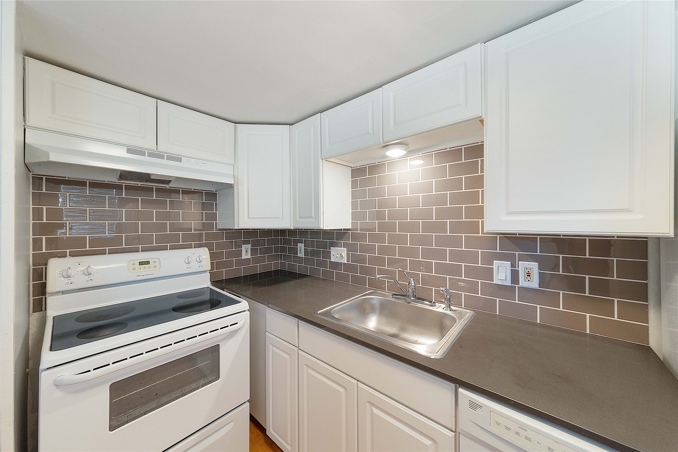 2500 Burleson Road, Unit 512 Austin, TX 78741 - Photo 2 of 16 Kitchen featuring white appliances, dark countertops, white cabinets, and backsplash