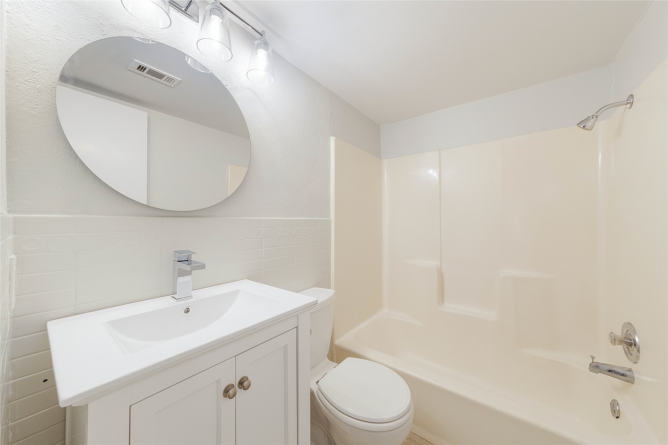 2500 Burleson Road, Unit 512 Austin, TX 78741 - Photo 5 of 16 Full bathroom featuring tile walls, vanity, a wainscoted wall, and washtub / shower combination
