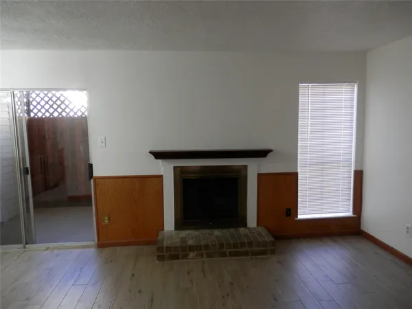 a view of an empty room with wooden floor and a fireplace