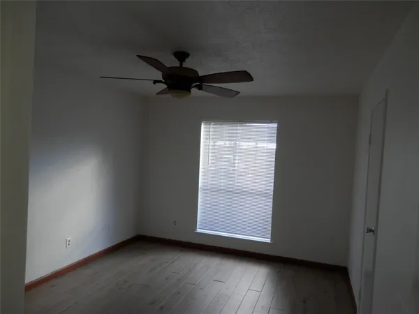 an empty room with wooden floor closet fan and windows