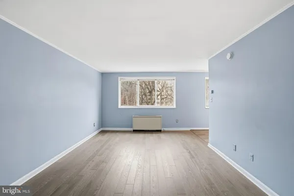 an empty room with wooden floor a ceiling fan and windows