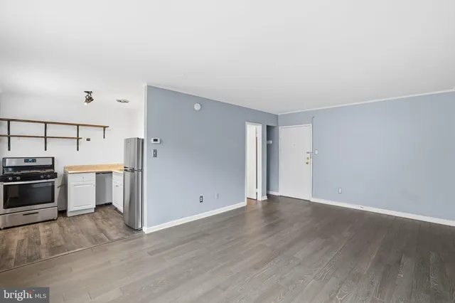 a view of a kitchen with a stove wooden cabinets and entryway