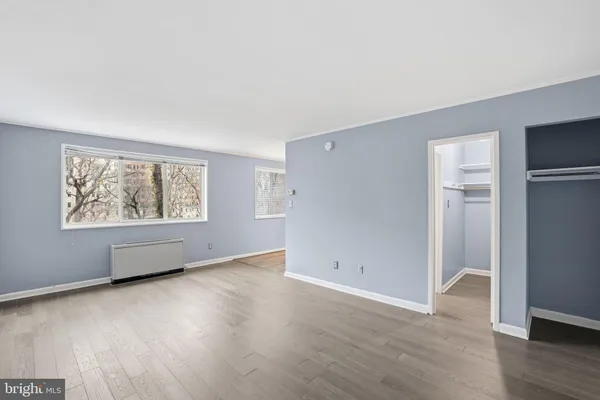 an empty room with wooden floor and windows