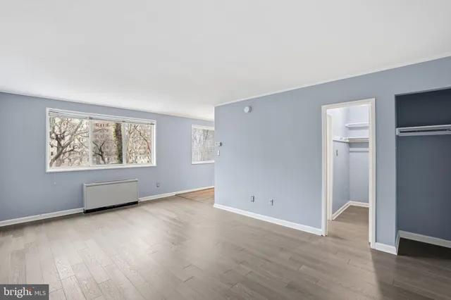 an empty room with wooden floor and windows
