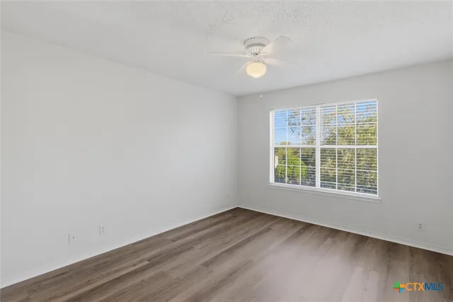 an empty room with wooden floor and fan