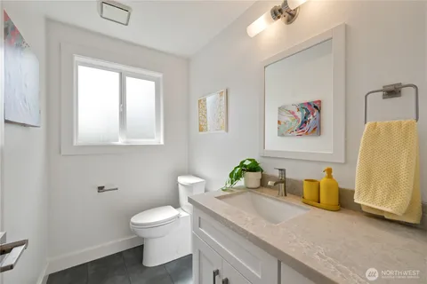 a bathroom with a granite countertop toilet sink and mirror