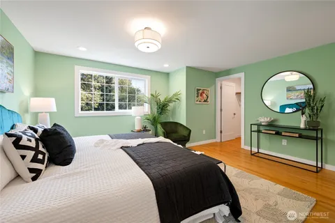 a bedroom with a bed windows and a large mirror