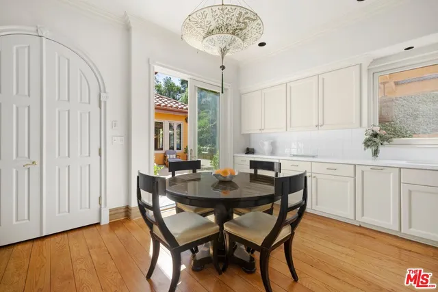 a dining room with wooden floor a chandelier a wooden table and chairs