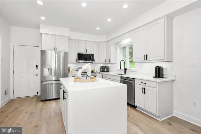 a kitchen with white cabinets sink and stainless steel appliances