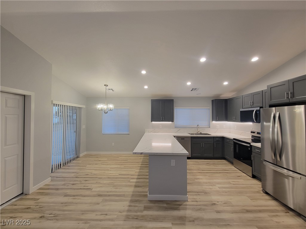 1021 East Manse Road Pahrump, NV 89048 - Photo 23 of 25 Kitchen featuring vaulted ceiling, stainless steel appliances, a peninsula, light wood-style floors, and gray cabinets