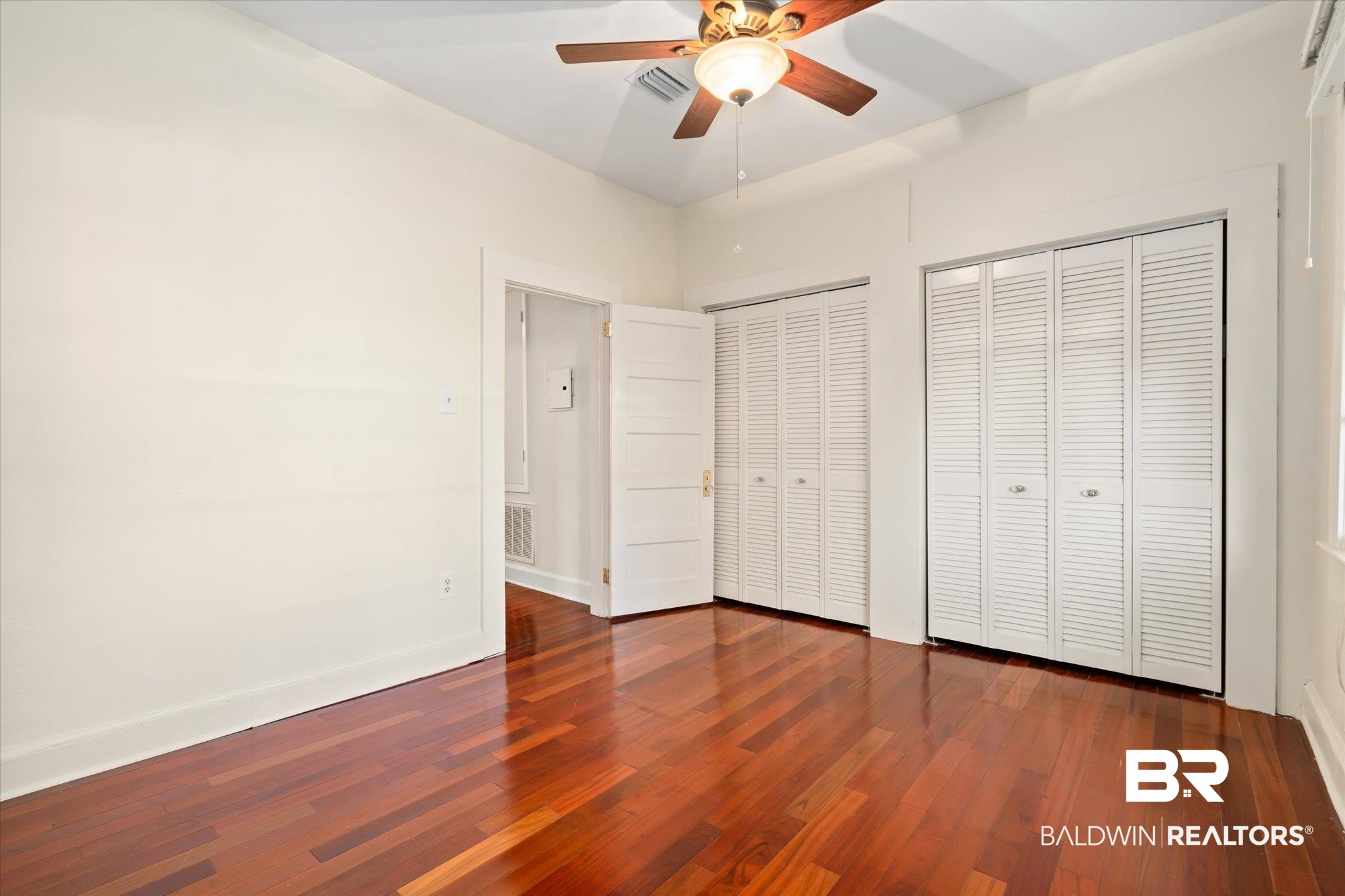 1220 Elmira Street Mobile, AL 36604 - Photo 9 of 20 Unfurnished bedroom with dark hardwood / wood-style flooring, two closets, and ceiling fan