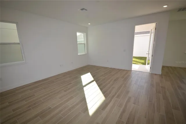 an empty room with wooden floor and windows