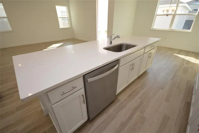 a kitchen with stainless steel appliances a sink a stove and white cabinets