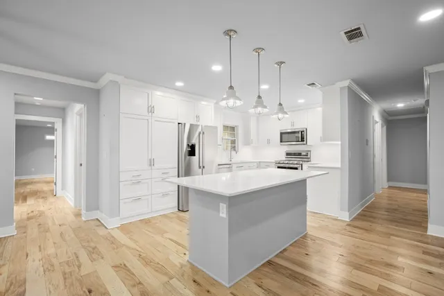 a large kitchen with stainless steel appliances kitchen island granite countertop a refrigerator and a sink