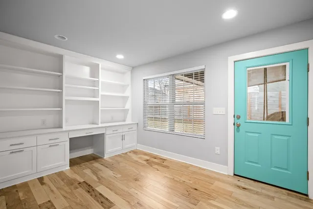 a view of an empty room with a window and wooden floor