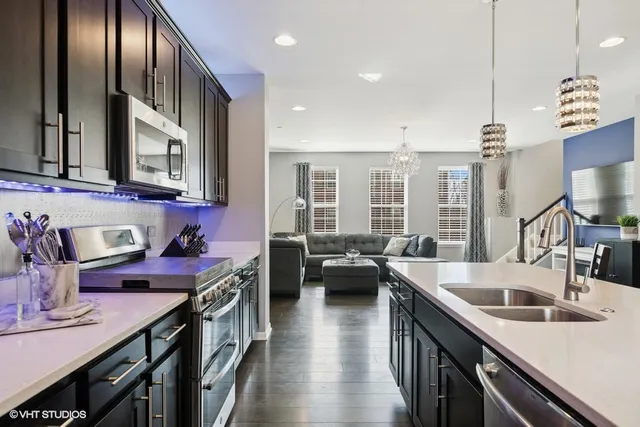 a kitchen with stainless steel appliances granite countertop a sink a stove and a wooden floors