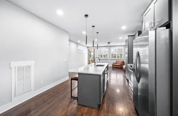 a kitchen with stainless steel appliances granite countertop a refrigerator a sink a stove and a wooden floors